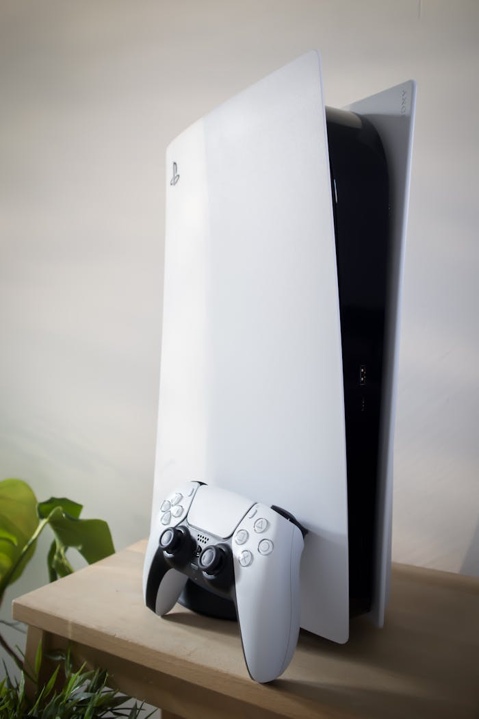 A sleek PlayStation 5 console with DualSense controller on a wooden table.